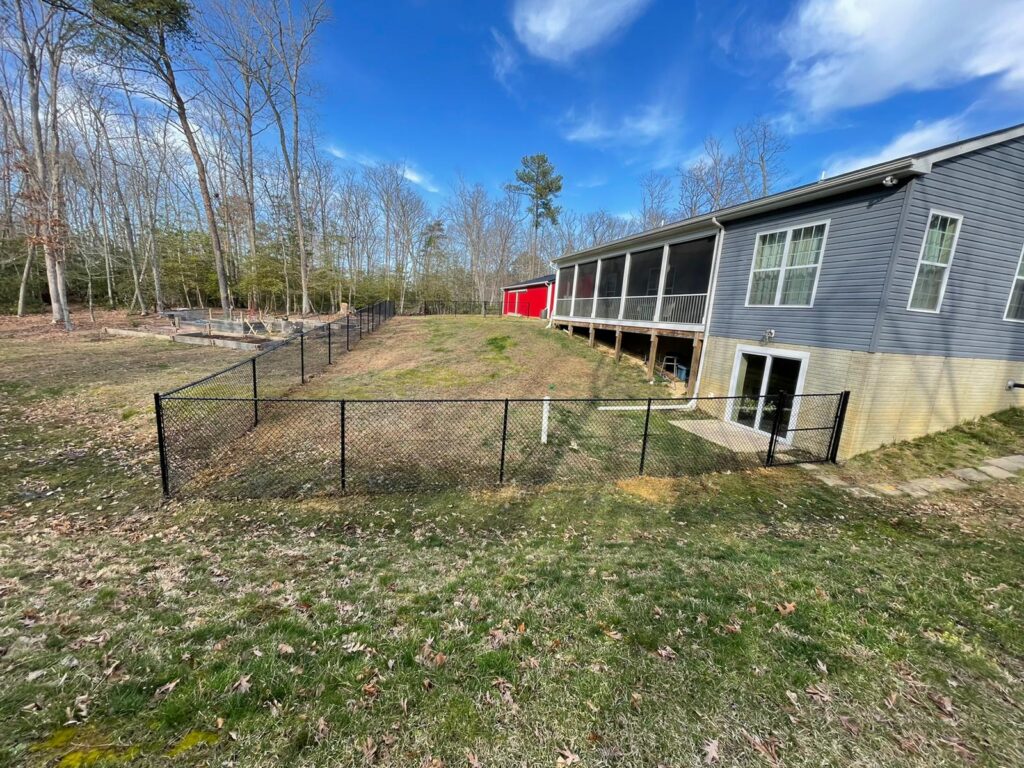 Black chain link fence around the back of a home with a walkout basement