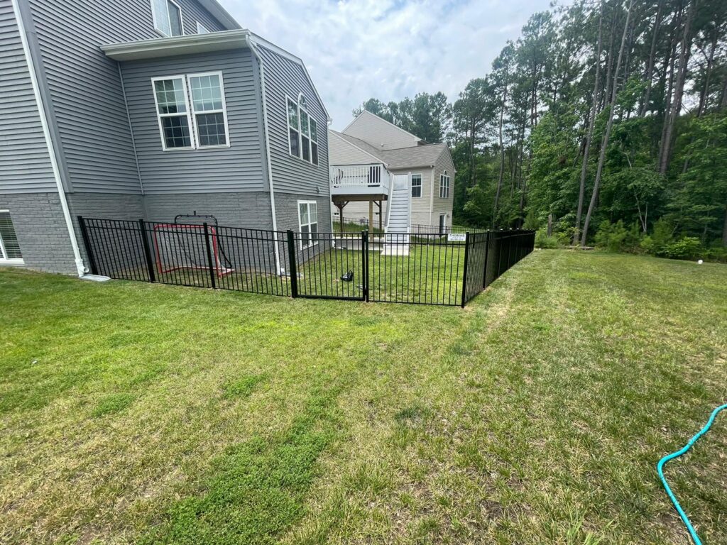 Black aluminum fence enclosing the backyard of a two-story home