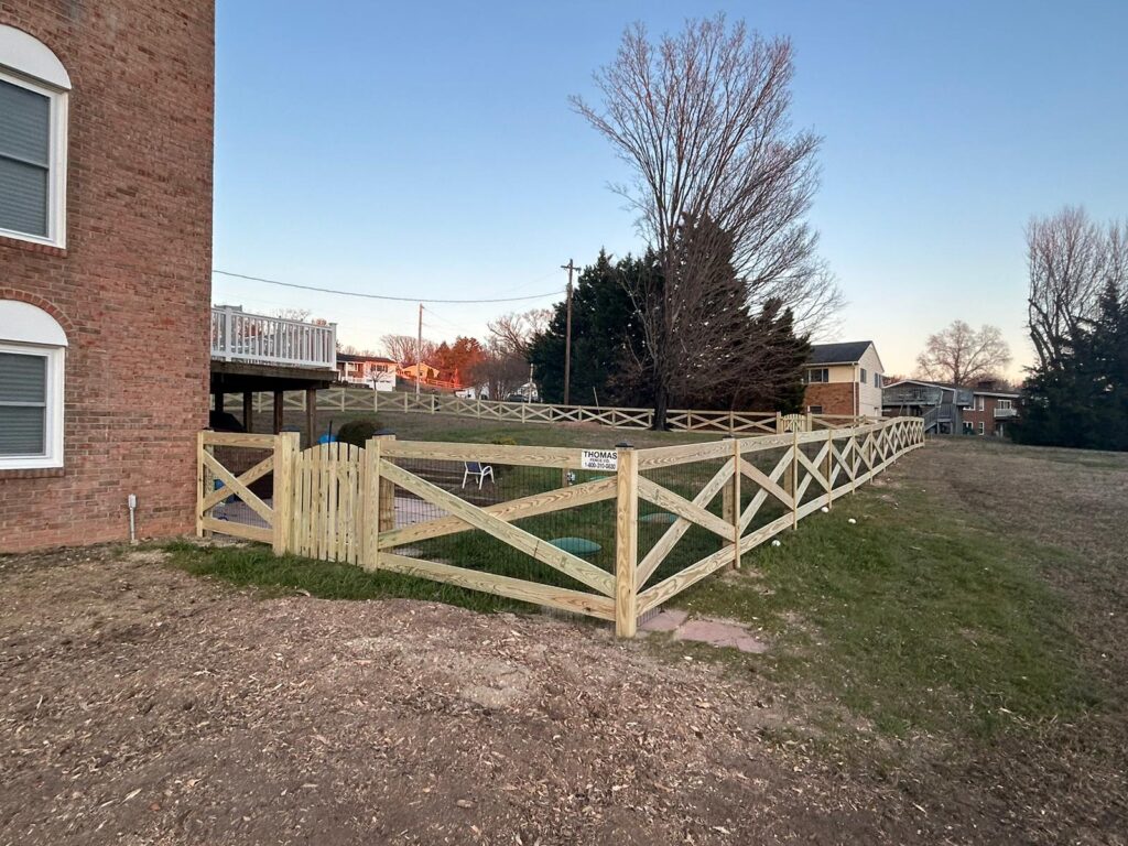 Wood cross buck rail fence beside a brick home