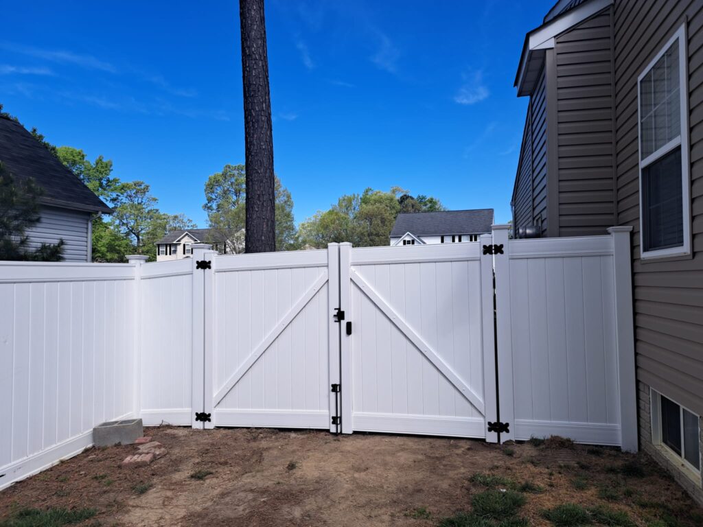 White vinyl privacy fence with a walk gate between two homes