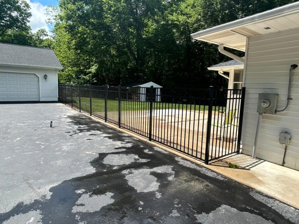 Black aluminum fence running along a driveway beside a garage