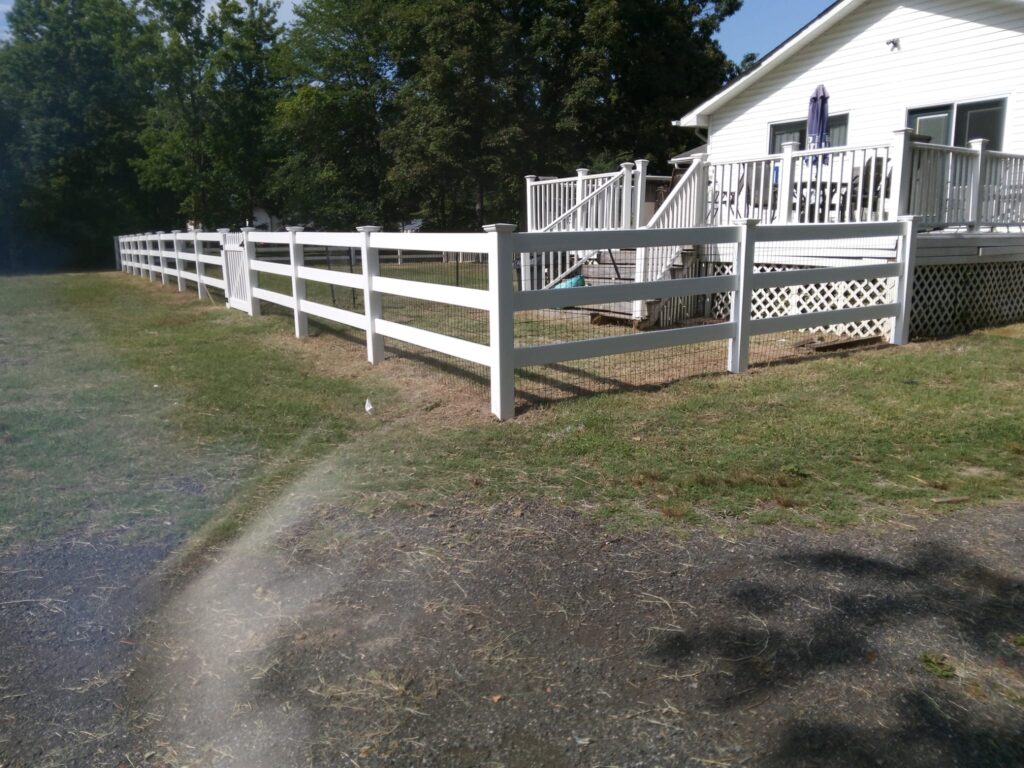 White vinyl ranch rail fence along a backyard path