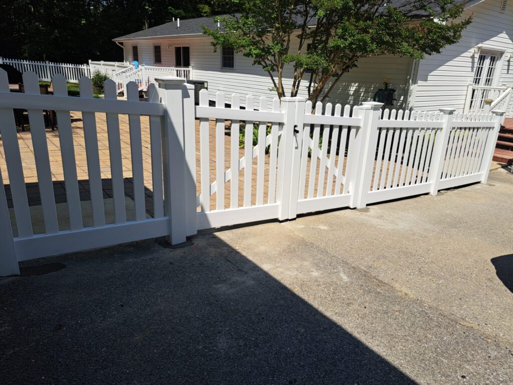 White vinyl picket fence and gate by a driveway