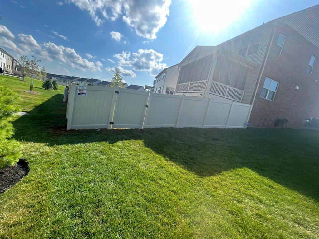 Tan vinyl privacy fence around a new backyard