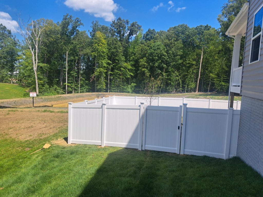 White vinyl privacy fence and gate at the side of a new home