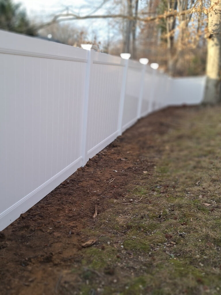 White vinyl privacy fence along a side yard after installation