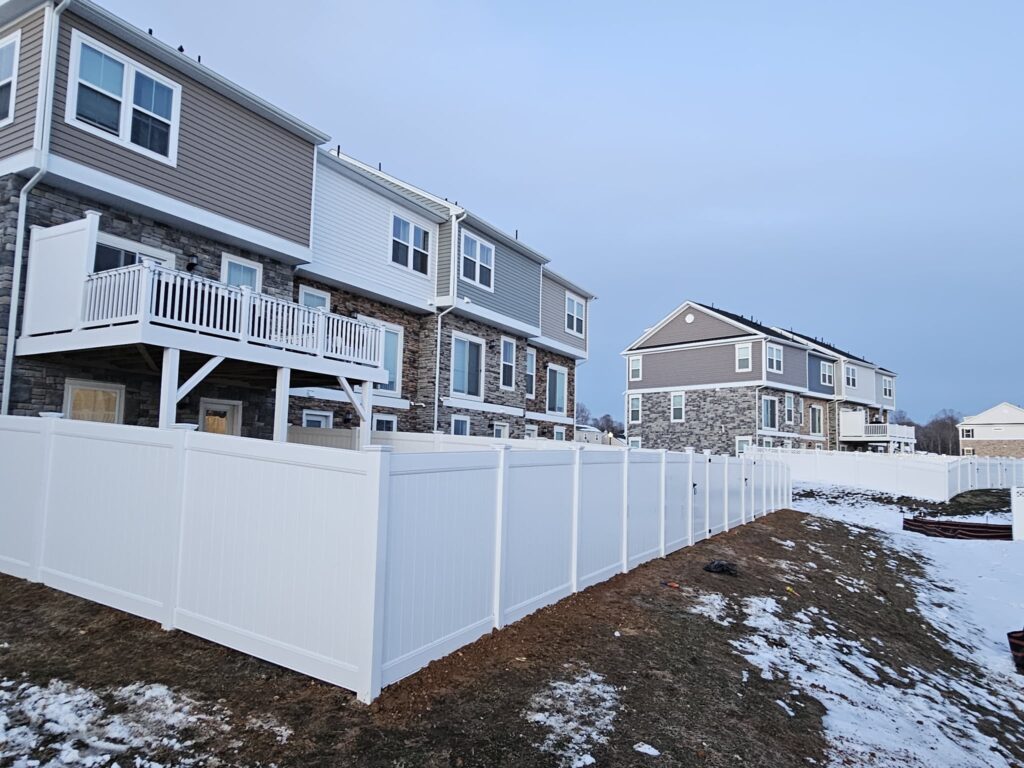 White vinyl privacy fence behind a row of townhouses