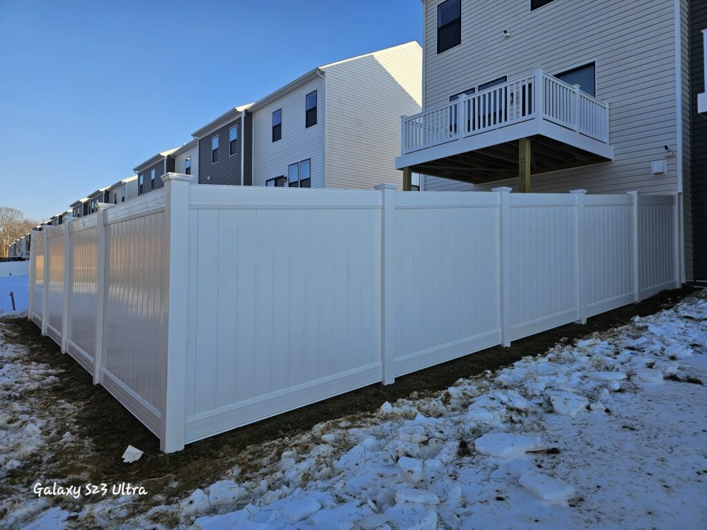 White vinyl privacy fence along a row of townhouse yards