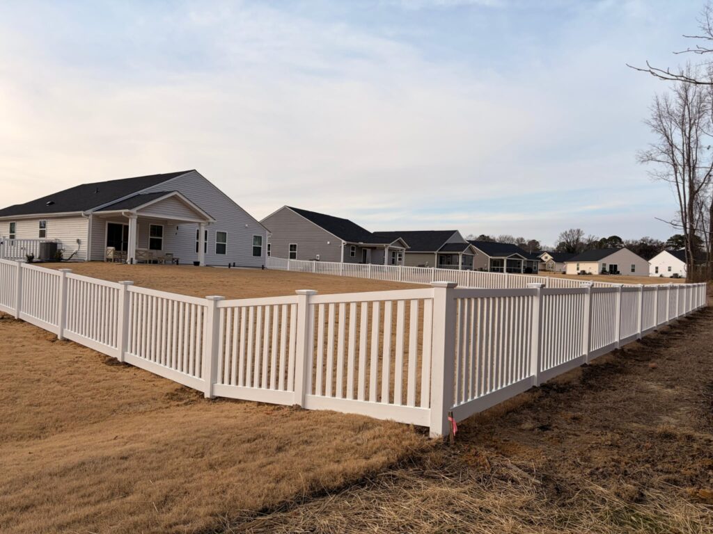 White vinyl picket fence around a new subdivision yard