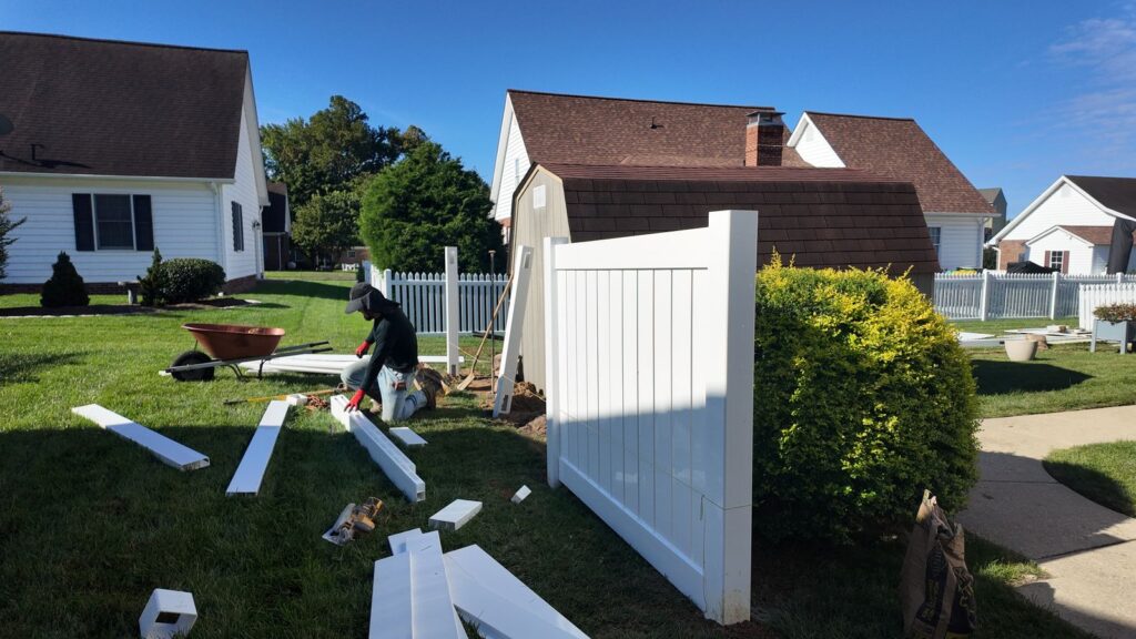 Old white vinyl fence being removed before replacement