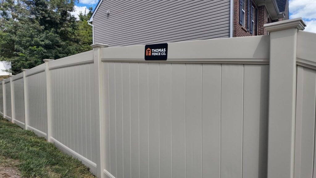 Corner of a new tan vinyl privacy fence