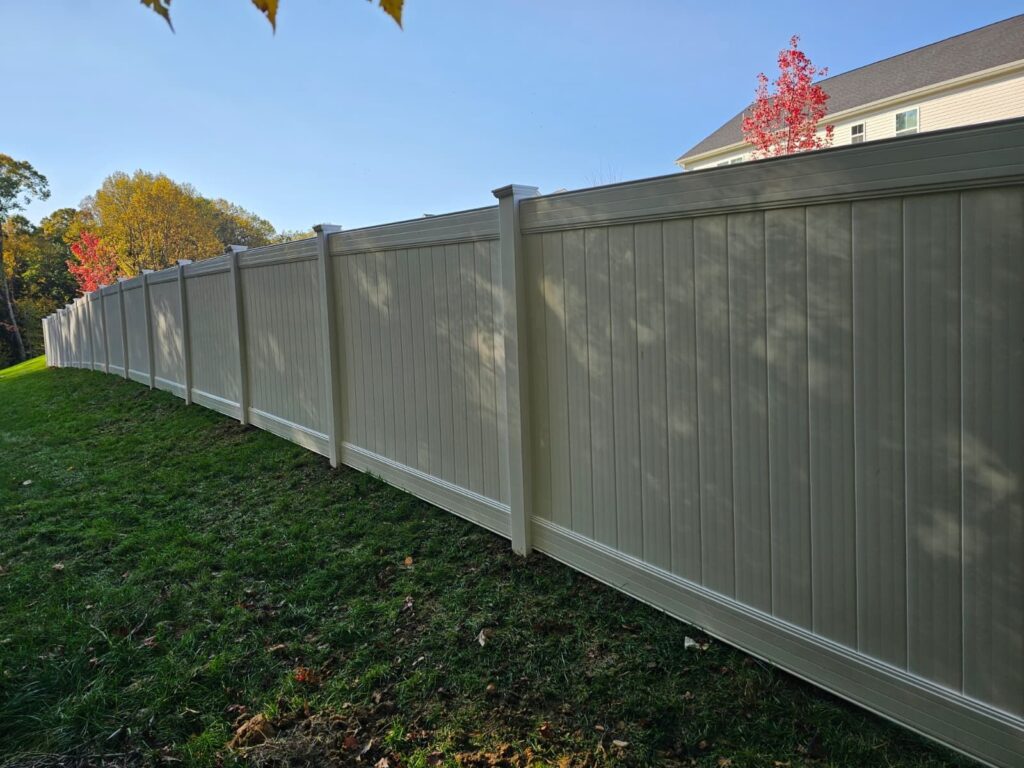 Long tan vinyl privacy fence along a lawn