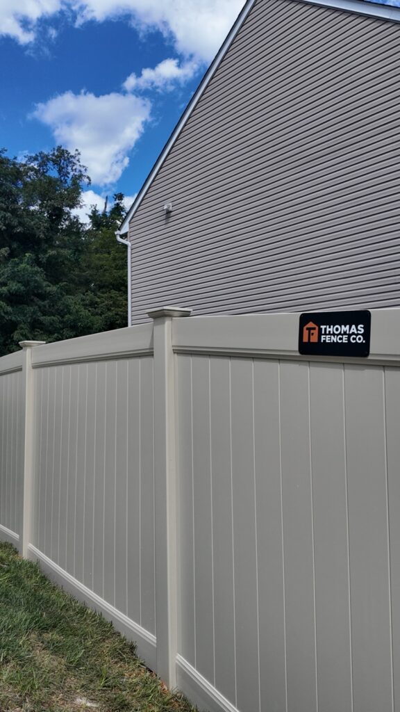 Tan vinyl privacy fence with a Thomas Fence Co sign in Myrtle Beach, SC